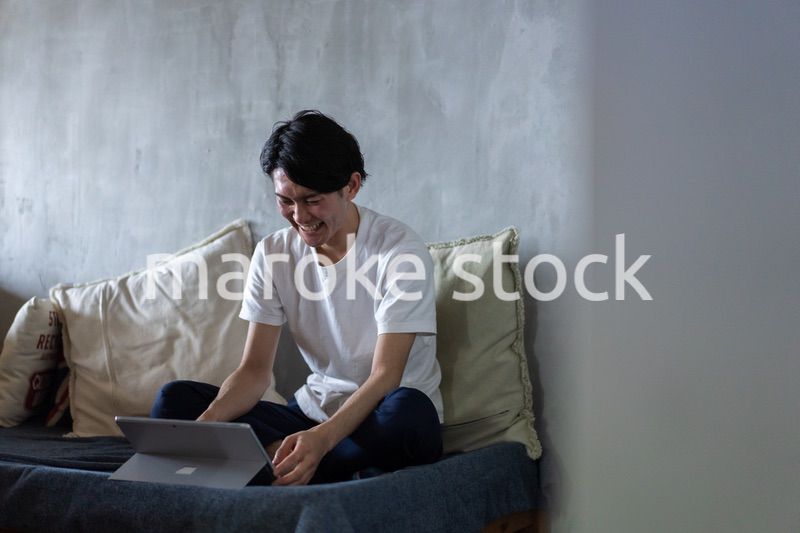 ベッドで在宅勤務をする若い男性