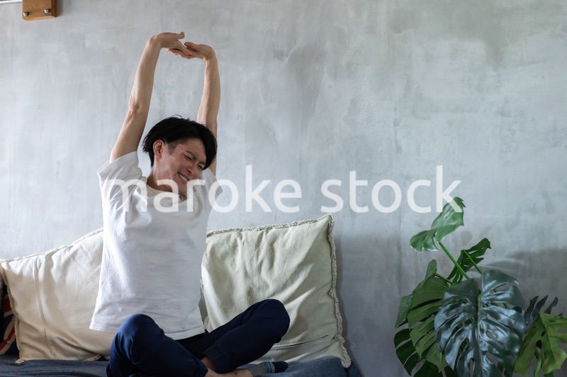 ベッドで伸びをする若い男性