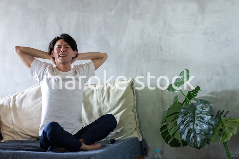 ベッドで伸びをする若い男性