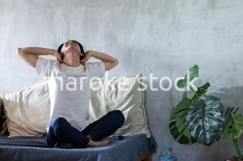 ベッドで伸びをする若い男性