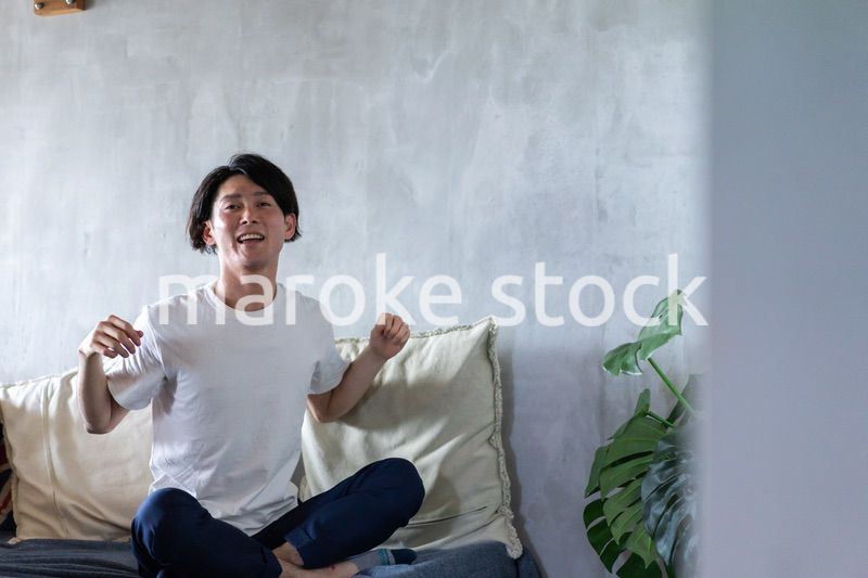 ベッドで伸びをする若い男性