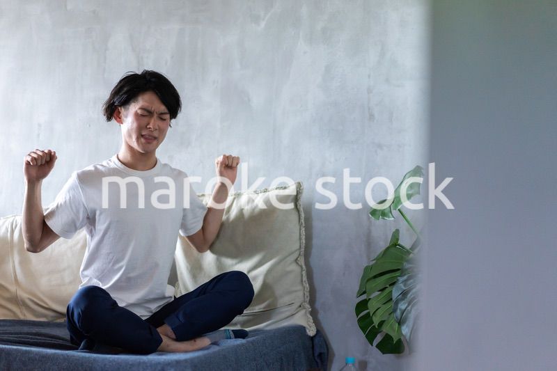 ベッドで伸びをする若い男性