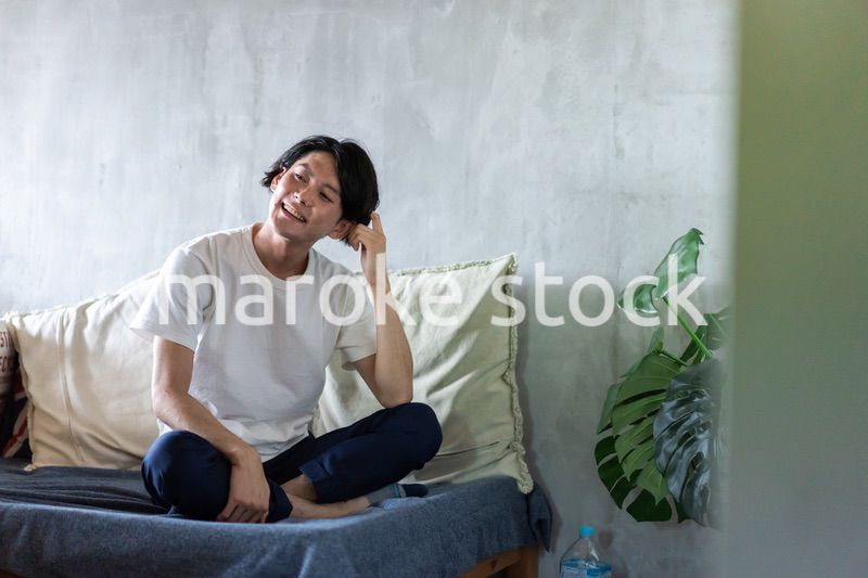 ベッドで伸びをする若い男性