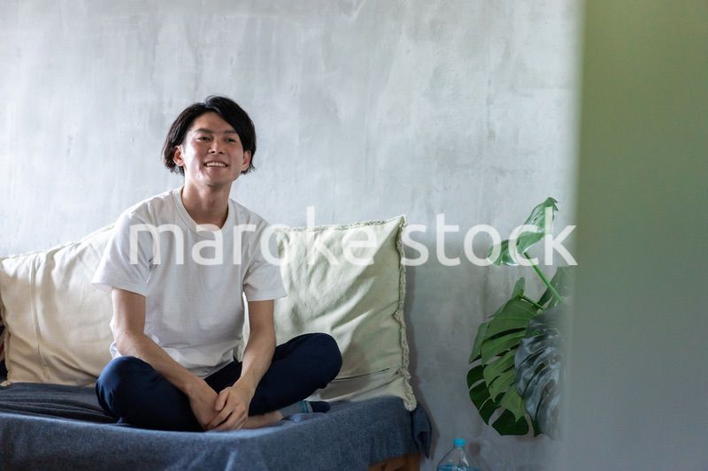 ベッドで伸びをする若い男性