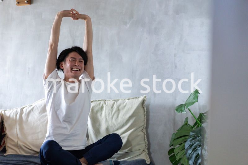 ベッドで伸びをする若い男性