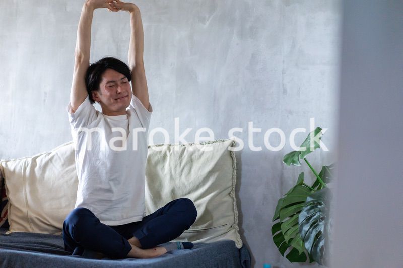 ベッドで伸びをする若い男性