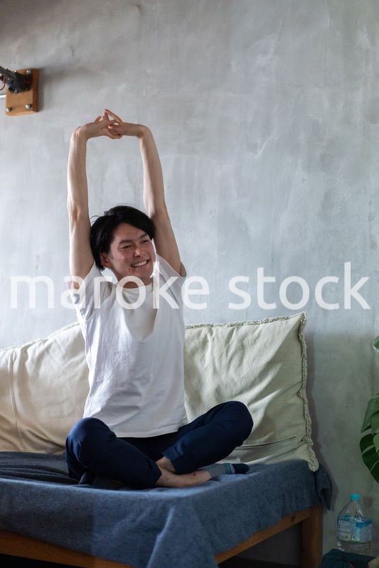 ベッドで伸びをする若い男性