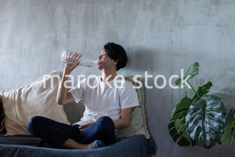 ベッドで水を飲む若い男性