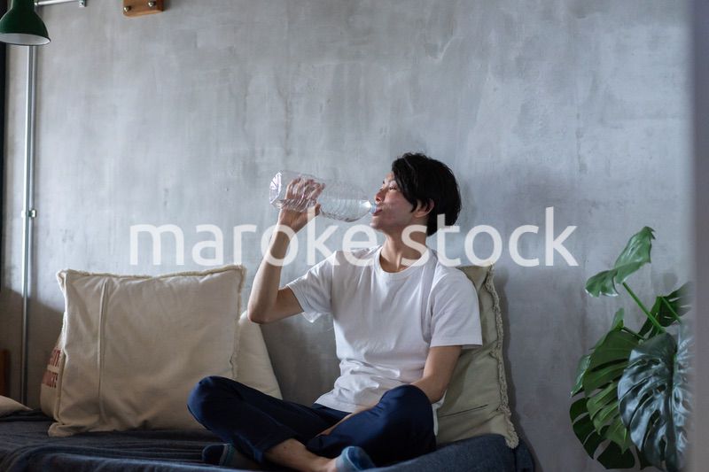ベッドで水を飲む若い男性