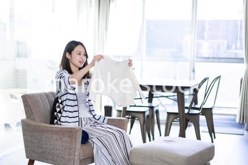 家で洗濯物をたたむ若い女性