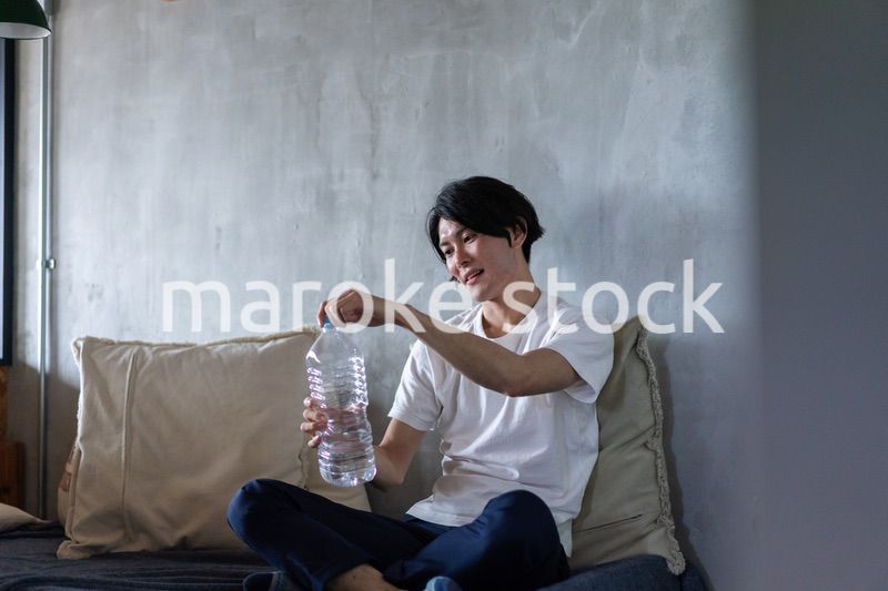 ベッドで水を飲む若い男性