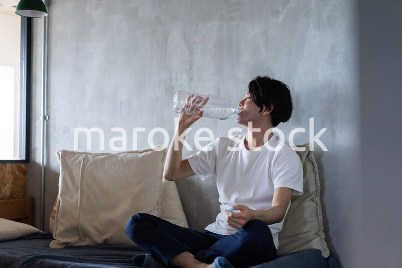 ベッドで水を飲む若い男性