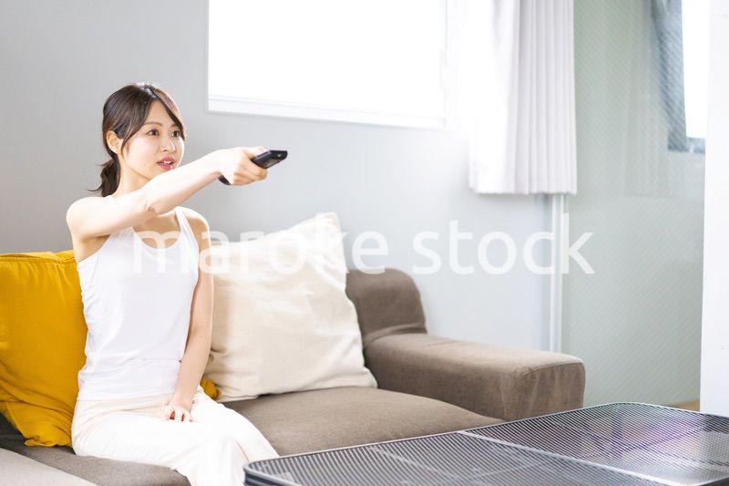 家でテレビを見る若い女性