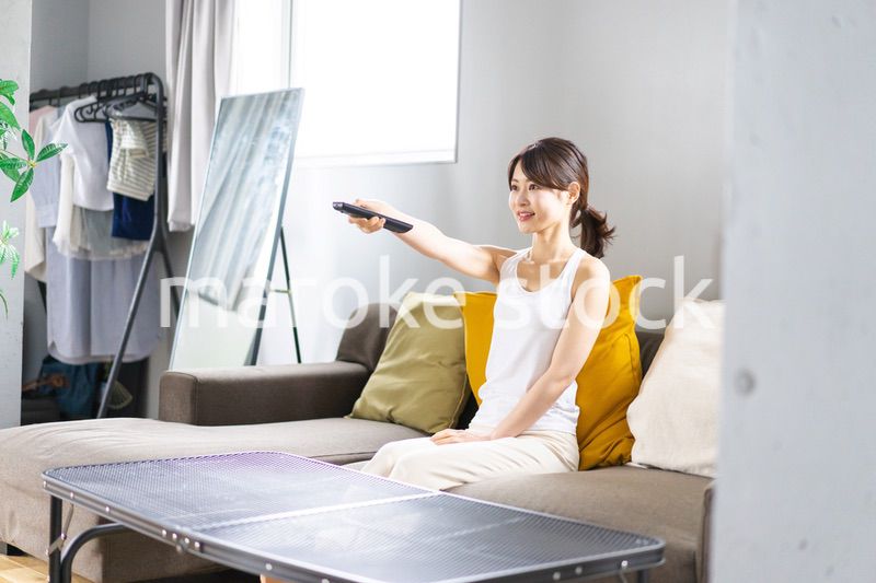 家でテレビを見る若い女性