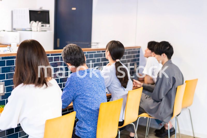 レストランのカウンター席でご飯を食べる人々
