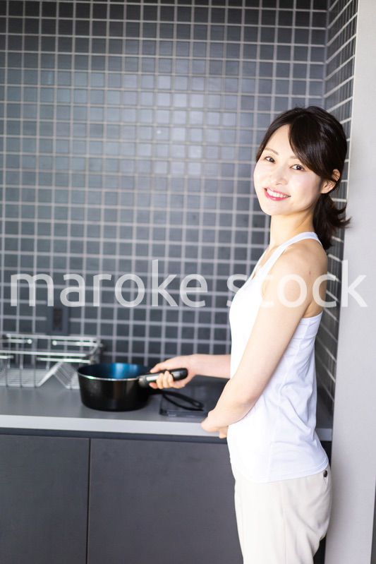 キッチンで料理をする若い女性