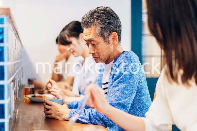 レストランのカウンター席でご飯を食べる人々