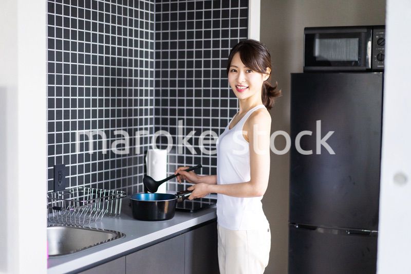 キッチンで料理をする若い女性