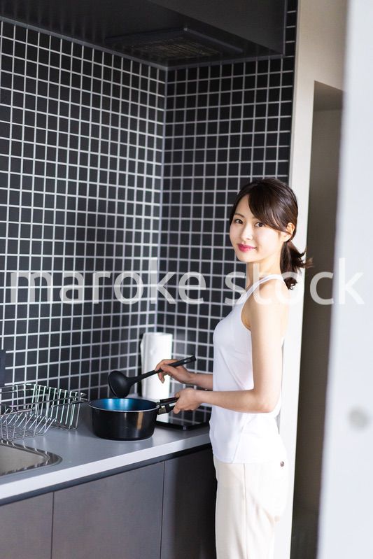 キッチンで料理をする若い女性