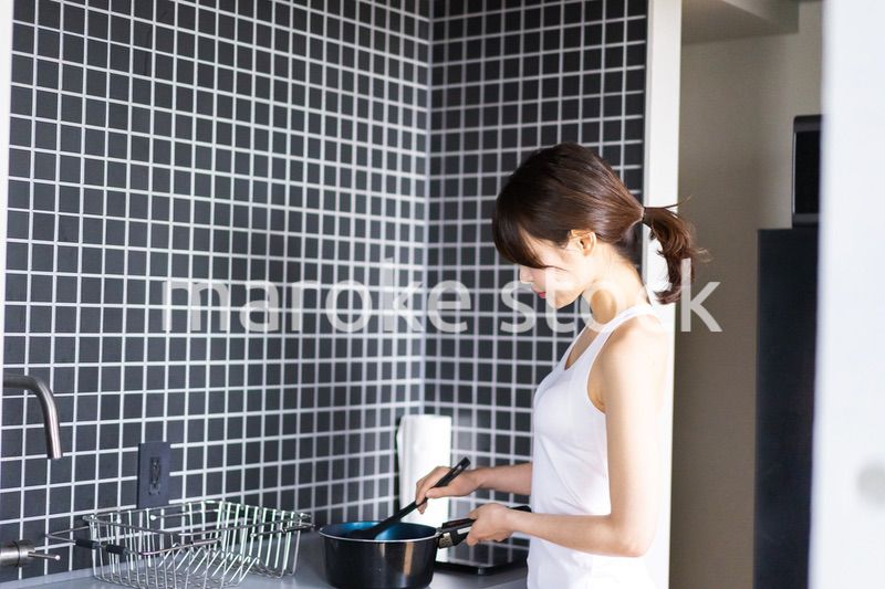 キッチンで料理をする若い女性