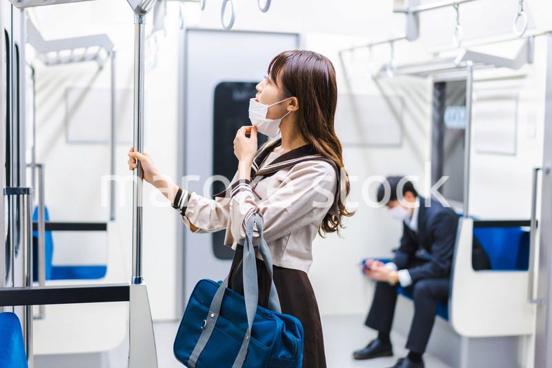 鼻だしマスクをして電車にのる女子高生