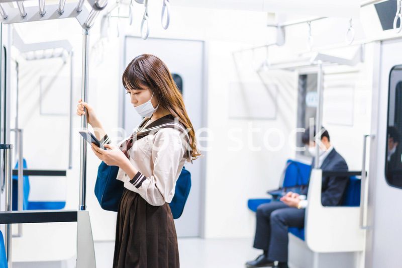 鼻だしマスクをして電車にのる女子高生