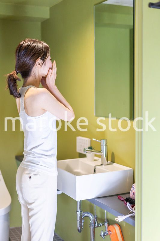 洗面台で顔を洗う若い女性
