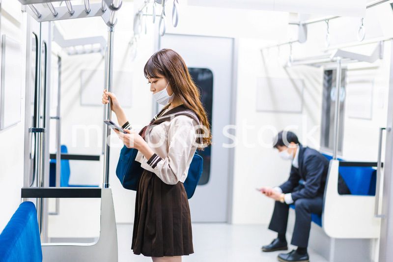 鼻だしマスクをして電車にのる女子高生