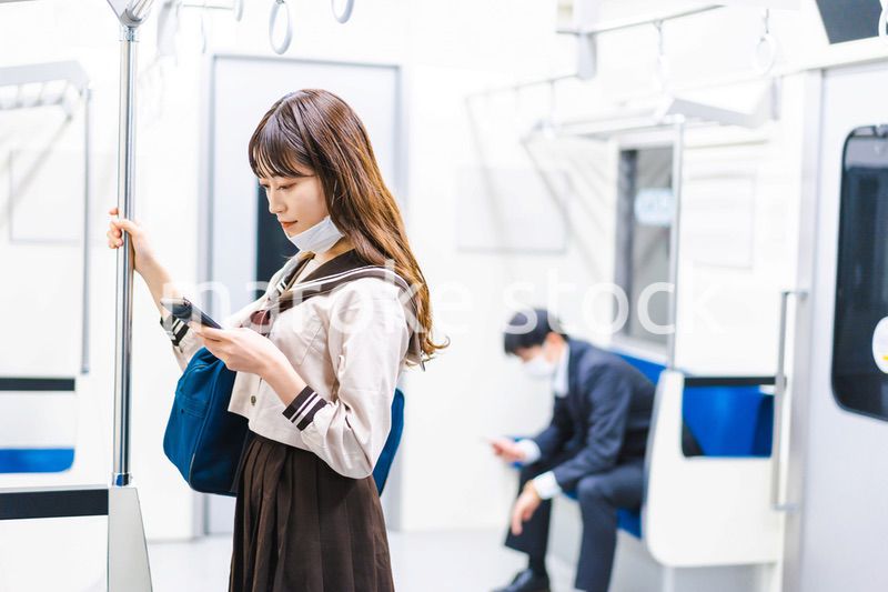 鼻だしマスクをして電車にのる女子高生