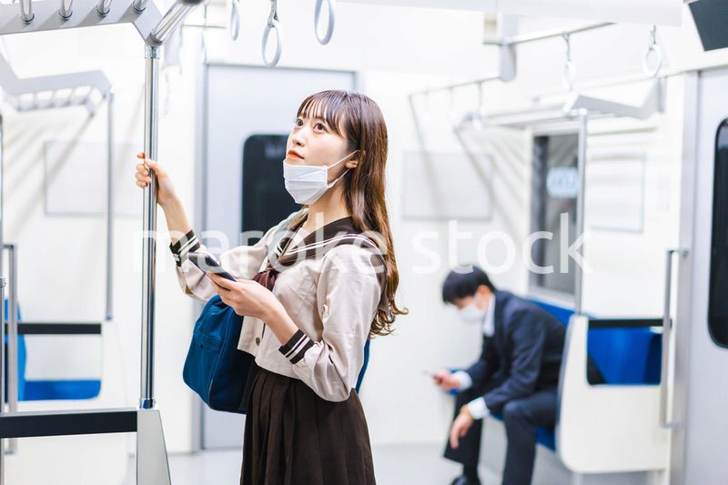 鼻だしマスクをして電車にのる女子高生