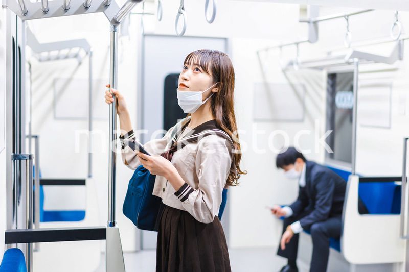 鼻だしマスクをして電車にのる女子高生