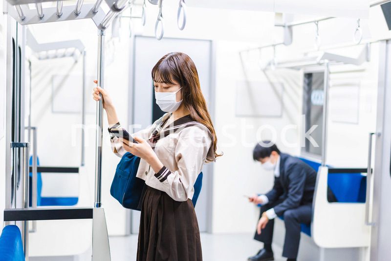 鼻だしマスクをして電車にのる女子高生