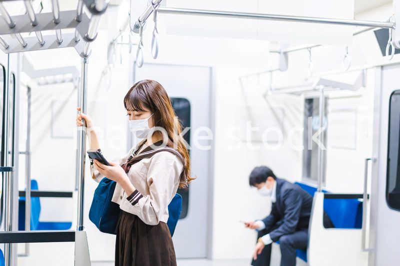 鼻だしマスクをして電車にのる女子高生