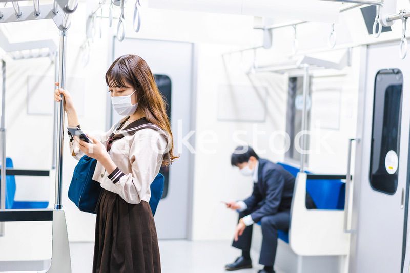 鼻だしマスクをして電車にのる女子高生