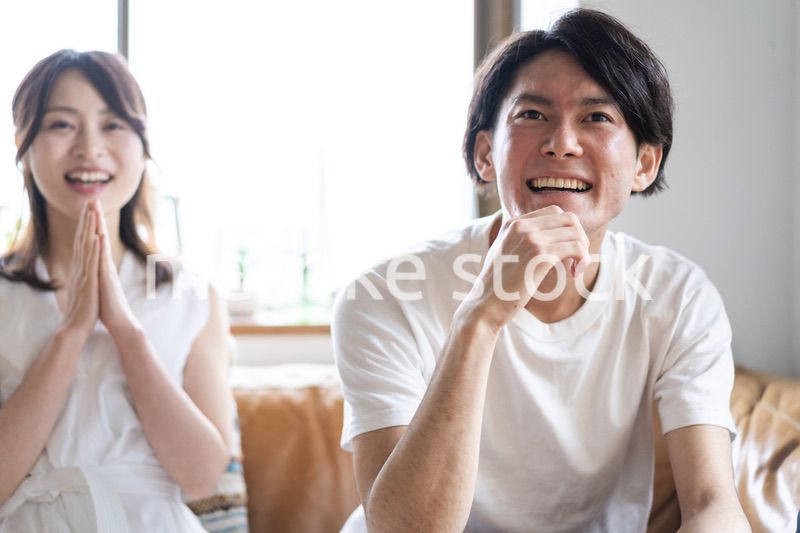 おうちでスポーツ観戦をするカップル