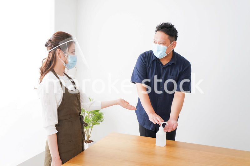 手のアルコール消毒をお願いするカフェスタッフ