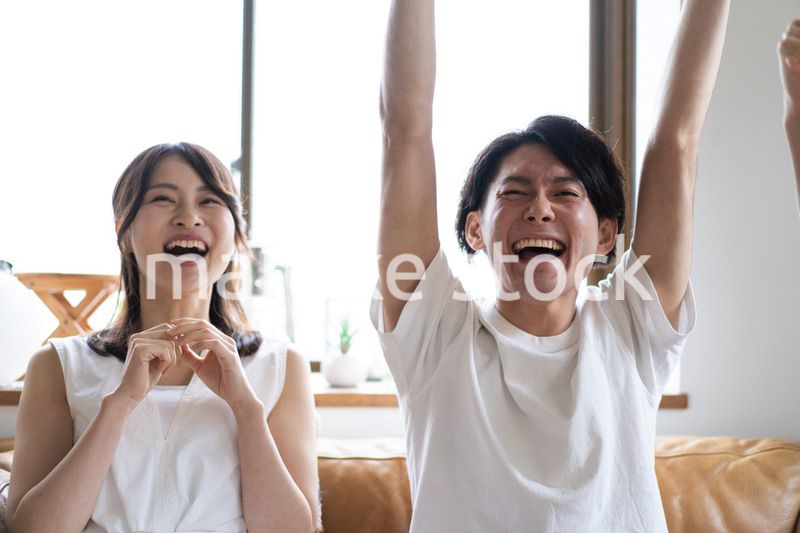 おうちでスポーツ観戦をするカップル