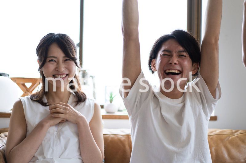 おうちでスポーツ観戦をするカップル