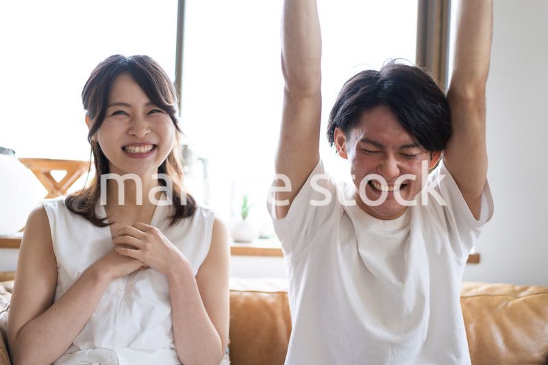 おうちでスポーツ観戦をするカップル