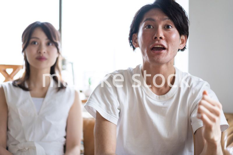 おうちでスポーツ観戦をするカップル