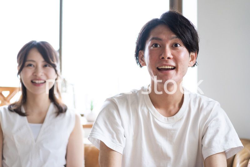 おうちでスポーツ観戦をするカップル