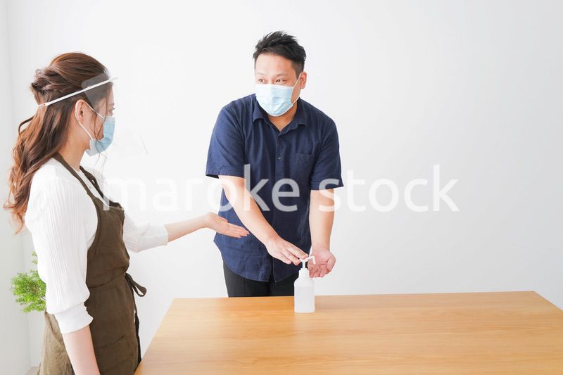 手のアルコール消毒をお願いするカフェスタッフ