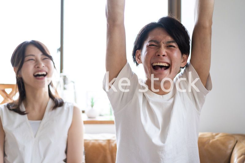 おうちでスポーツ観戦をするカップル