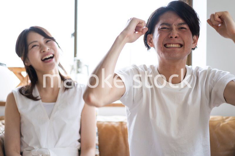 おうちでスポーツ観戦をするカップル