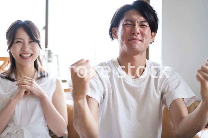 おうちでスポーツ観戦をするカップル