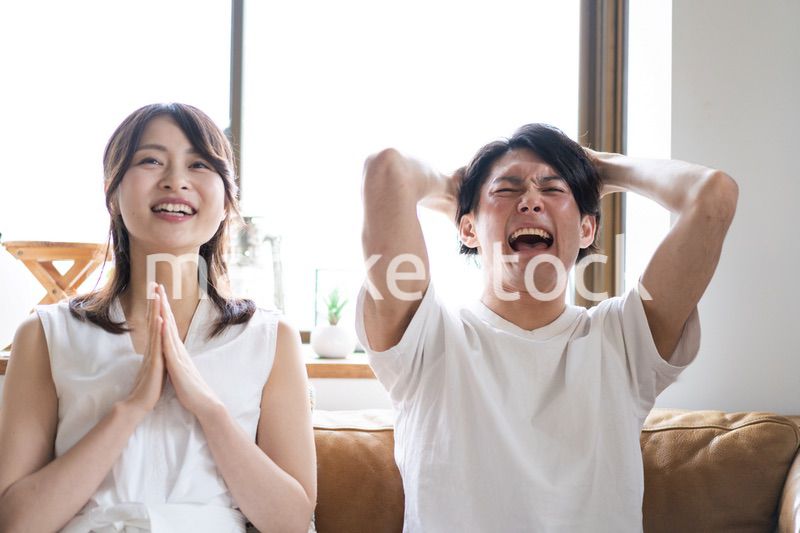 おうちでスポーツ観戦をするカップル