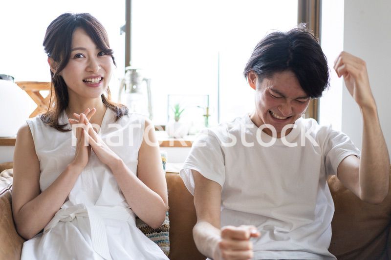 おうちでスポーツ観戦をするカップル