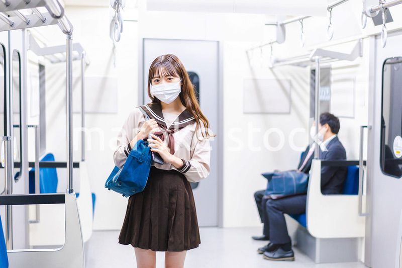 マスクをして電車通学をする女子高生