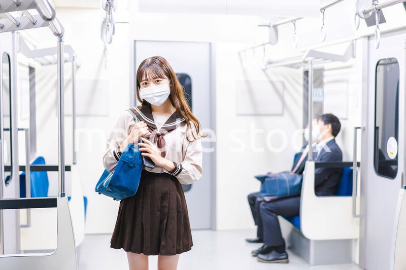 マスクをして電車通学をする女子高生