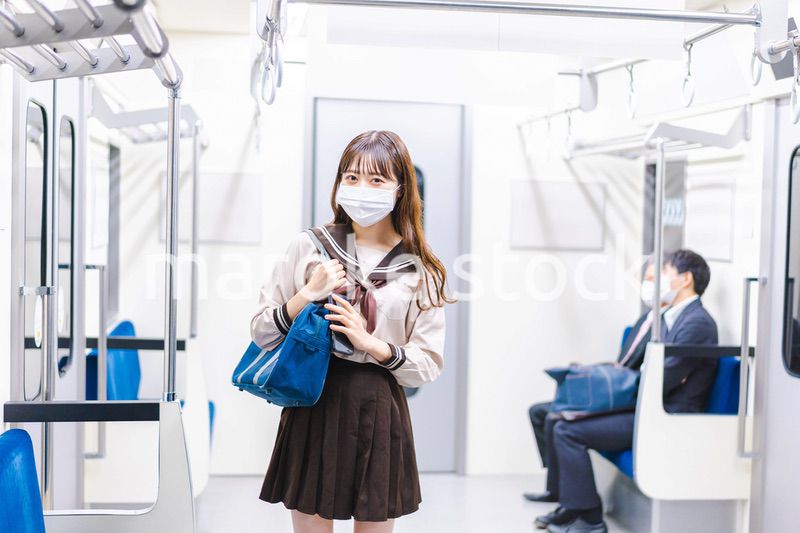 マスクをして電車通学をする女子高生